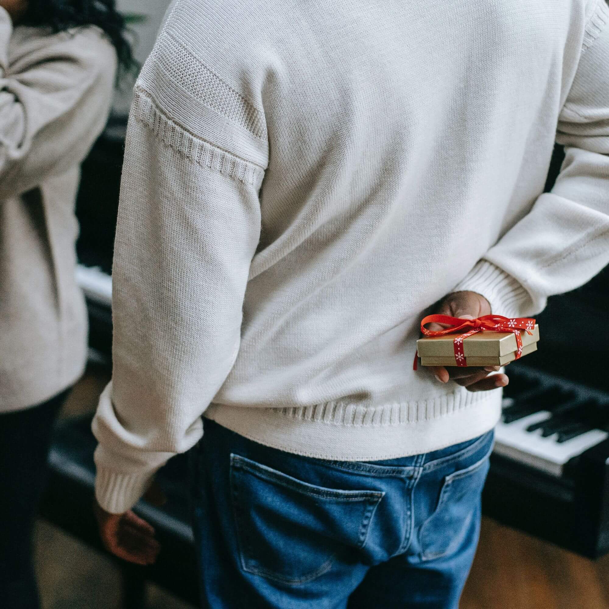 A man holding a Christmas gift wrapped in red ribbon