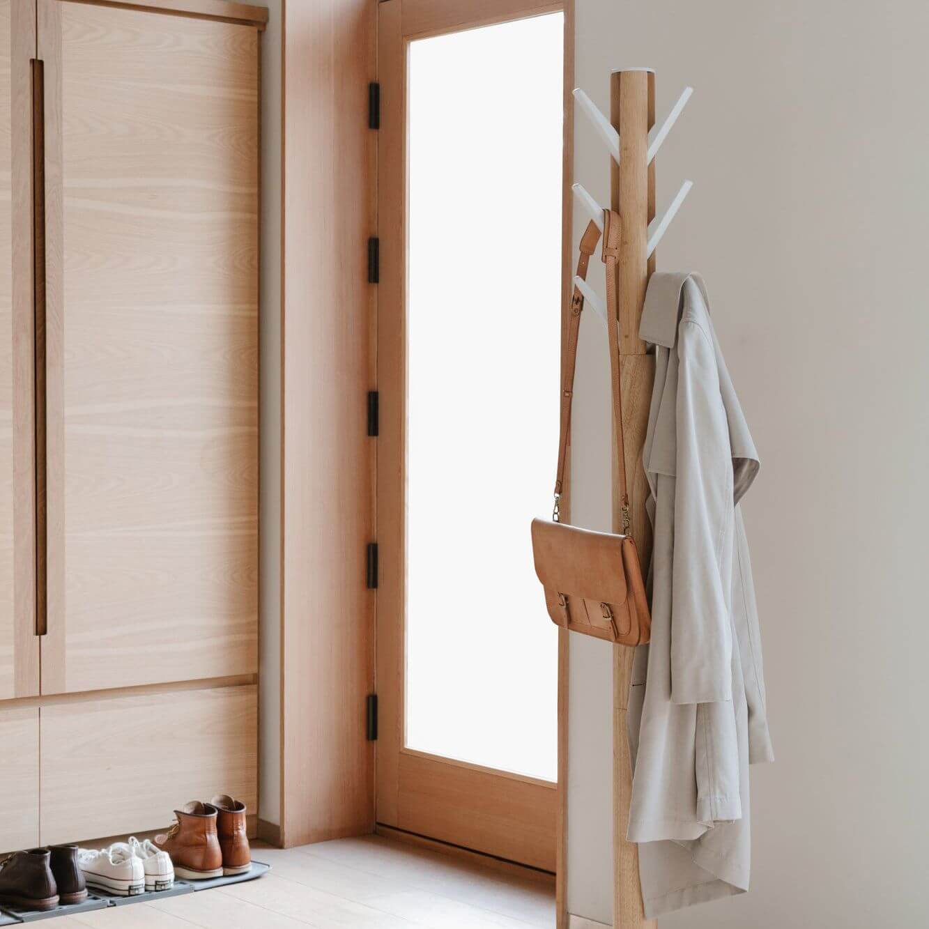 Timber coat rack standing next to a glass door