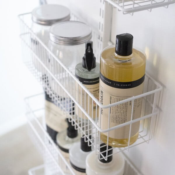 Bottles and jars stored in White Elfa Wire Utility Baskets