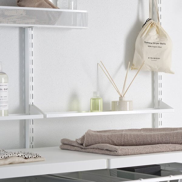 Two White Elfa Reversible Metal Shelf Trays installed above a laundry bench