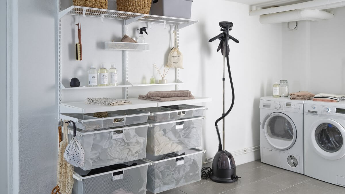 A White Elfa shelving setup in a laundry, with clothes, laundry bottles and cleaning supplies organised