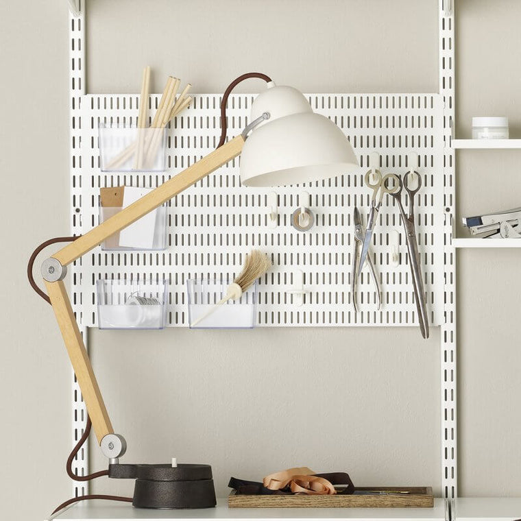 A White Elfa Storing Board installed above an office desk, organising stationery and office supplies