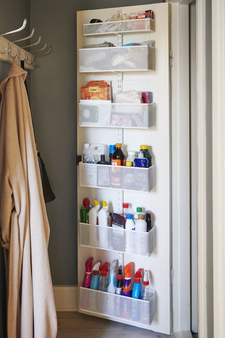 A White Elfa Utility Wall & Door system with Mesh Utility Baskets, used for over-the-door storage of bottles in a pantry or laundry