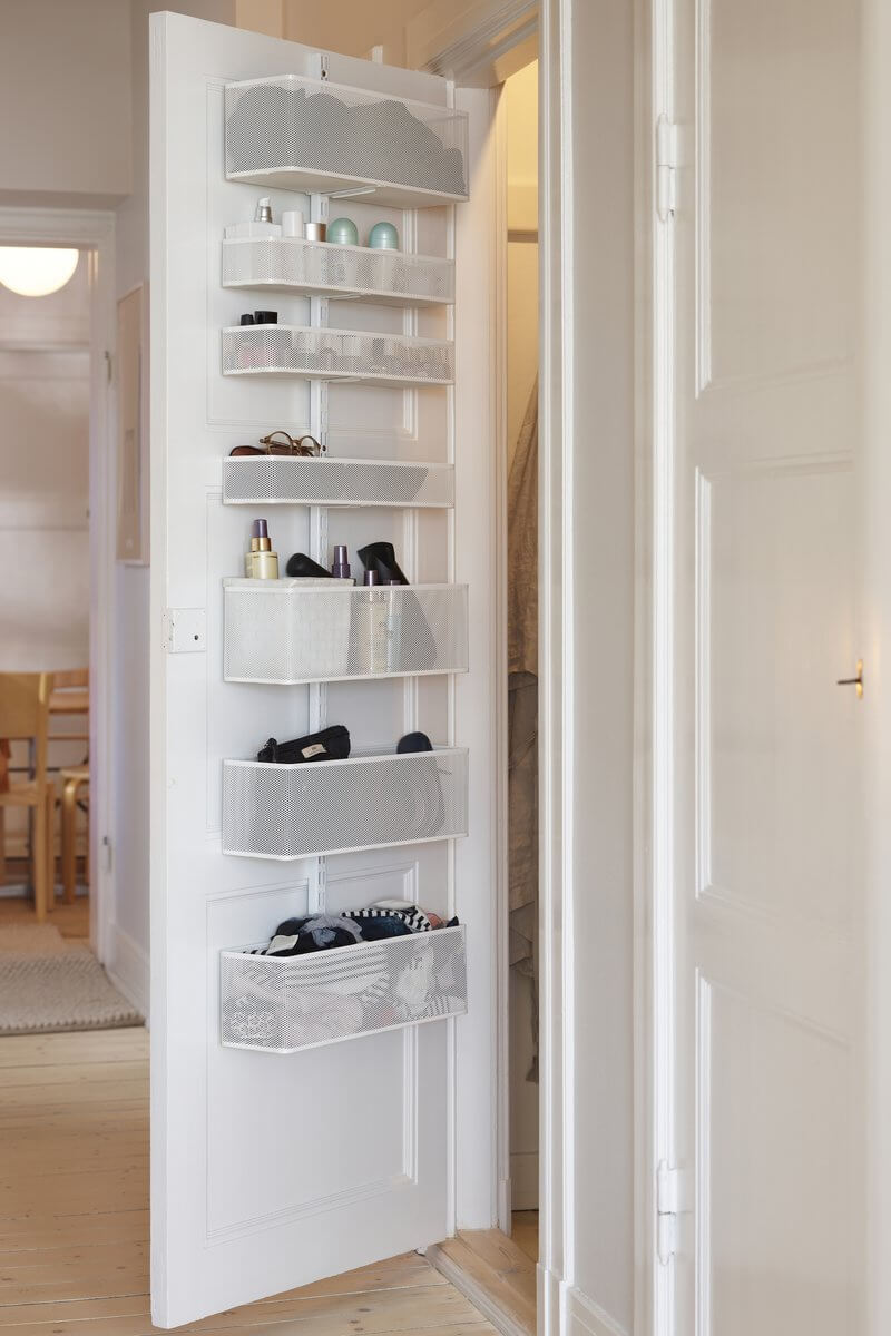 A White Elfa Utility Wall & Door system with Mesh Utility Baskets, used for over-the-door bedroom and bathroom storage